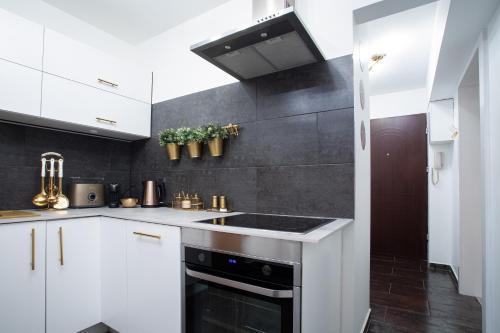 a kitchen with white cabinets and a sink at Katowice Golden Peacock - Grazynskiego 7 in Katowice