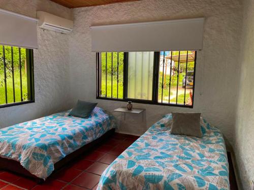 a bedroom with two beds and two windows at Villa Zunilda in Rivera