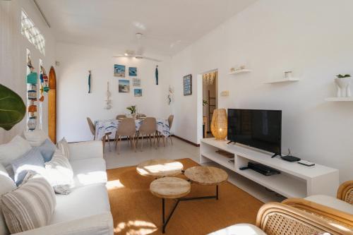 un salon avec un canapé blanc et une télévision dans l'établissement Coco Beach I&II - 6 Bedrooms , Private Pool , Beach at 200 meters, à Pointe aux Cannoniers