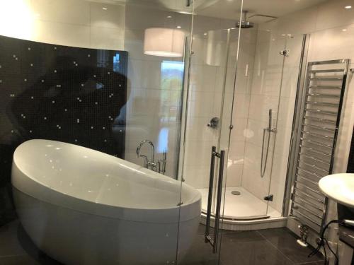 a bathroom with a tub and a shower and a sink at Luxus Seeappartements in Velden am Wörthersee