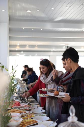 a group of people standing around a buffet line with plates of food at Destination Resort Thandiani in Abbottabad