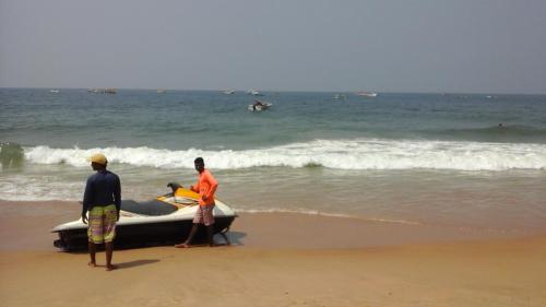 two men standing on the beach with a boat at Premium Luxury -1BHK at Candolim Beach with Free Wifi and Pool in Candolim
