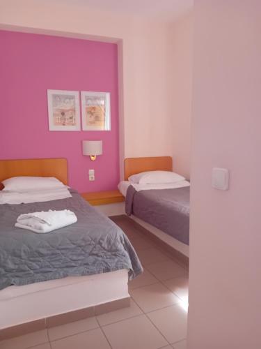 a bedroom with two beds and a purple wall at Heliotopos Apartments in Tolo