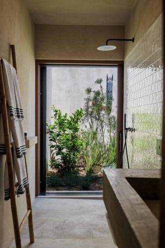 a bathroom with a large glass door to a yard at Velvet Bungalow in Carvalhal