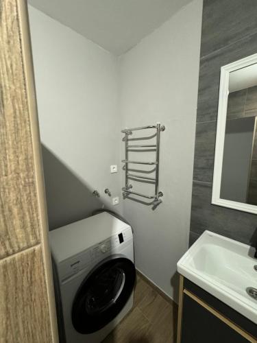 a washing machine in a bathroom next to a sink at Стильна і сучасна квартира з двома спальнями біля Дніпра! in Cherkasy