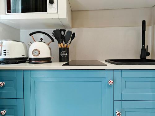 a kitchen with blue cabinets and a toaster and utensils at Zebbuga Deluxe Balcony Suite Apartment 4 in Żebbuġ