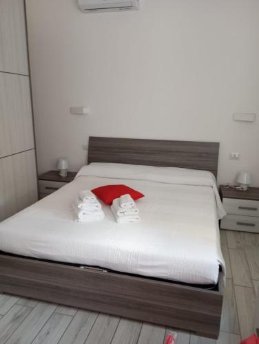 a bedroom with a white bed with a red pillow at Diana's in Stintino