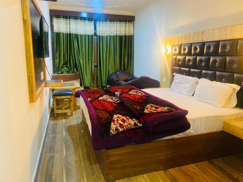 a bedroom with a bed and a chair and a television at Hotel Thakur Manali in Manāli