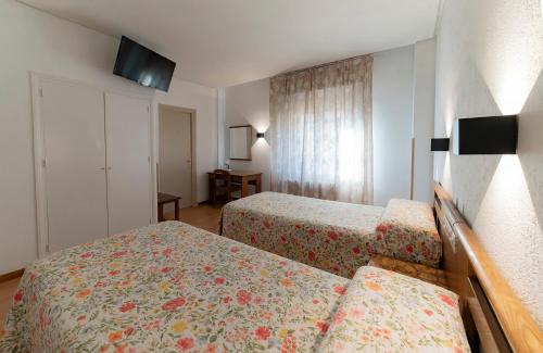 a hotel room with two beds and a television at Hotel Pedro Torres in Cuenca