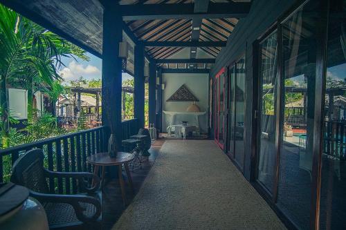 a porch of a house with chairs and a table at Baan Suan Residence เฮือนพักบ้านสวน in Chiang Mai