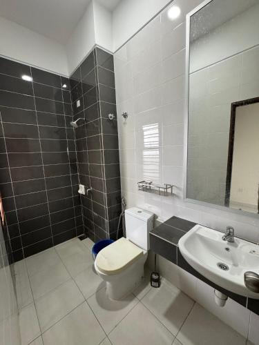 a bathroom with a toilet and a sink and a mirror at FA homestay in Kuantan