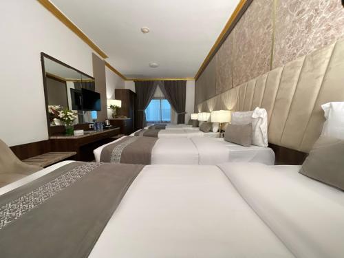 a hotel room with four beds and a mirror at Odest in Al Madinah