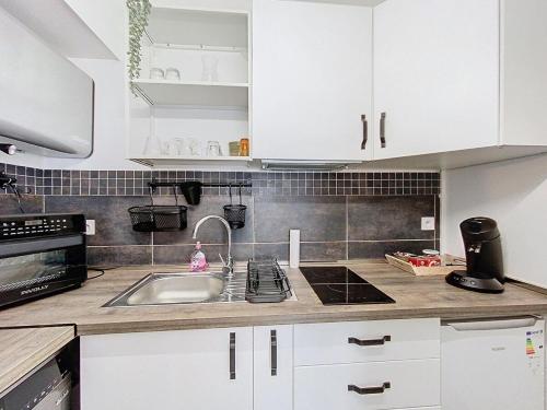 une cuisine avec des armoires blanches et un évier dans l'établissement Studio Lumineux Avignon Parking, à Avignon