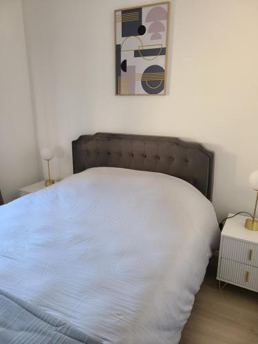 - une chambre dotée d'un lit blanc avec une photo sur le mur dans l'établissement Le N5 Cernay Centre, à Cernay