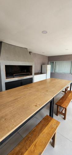 a large wooden table in a kitchen with benches at Aparts Magallanes in Presidente Derqui