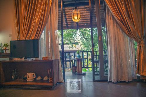 a living room with a tv and a large window at Baan Suan Residence เฮือนพักบ้านสวน in Chiang Mai