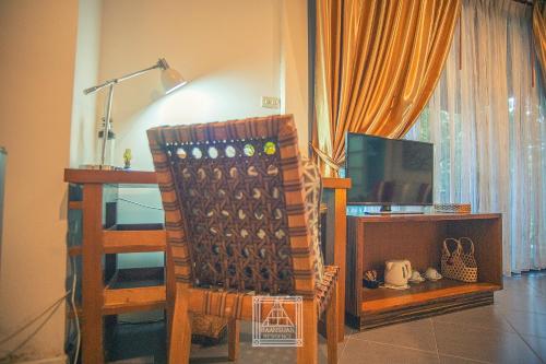 a living room with a chair and a television at Baan Suan Residence เฮือนพักบ้านสวน in Chiang Mai