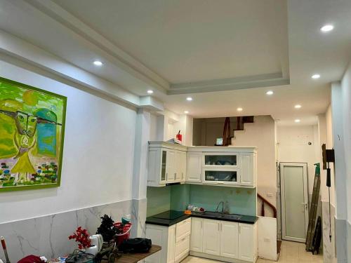 a kitchen with white cabinets and a painting on the wall at HnHome89TL in Hanoi