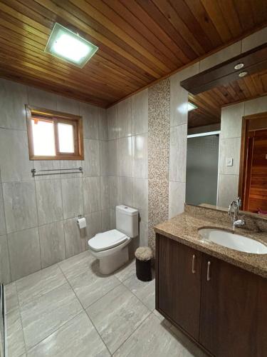 a bathroom with a toilet and a sink and a window at Aconchego e Tranquilidade in Lages