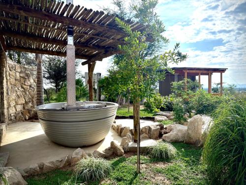 a large tub in a garden with a wooden pergola at Ndefu Self Catering Accommodation in Otjiwarongo