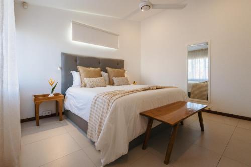Un dormitorio con una cama, una mesa y un espejo. en Coco Beach II - Seaside Home , Pool , Beach at 200 meters, en Grand Baie