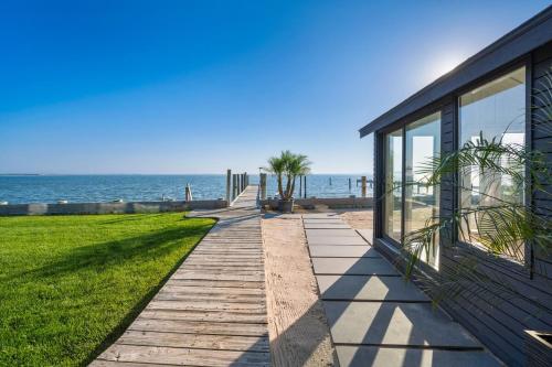 a walkway next to a house next to the ocean at Private beach on a fenced in property sunset views in Hampton Bays
