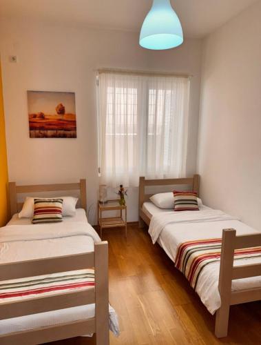 two beds in a small room with a window at Apartment Kristijan in Kotor