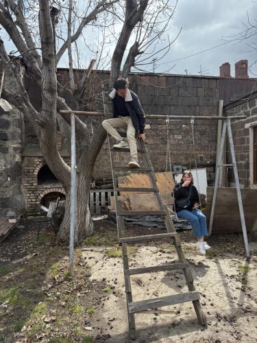 a man standing on a ladder next to a tree at HeyTun Gyumri in Gyumri