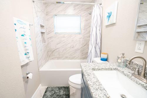 a white bathroom with a tub and a toilet and a sink at University Luxe Residences in Tampa