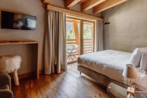 a bedroom with a bed and a television on a wall at Au Charmant Petit Lac - Ecohotel Parc & Spa in Champoluc