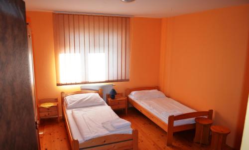 2 Betten in einem Zimmer mit orangefarbenen Wänden in der Unterkunft Villa Silver Green in Žarnovica