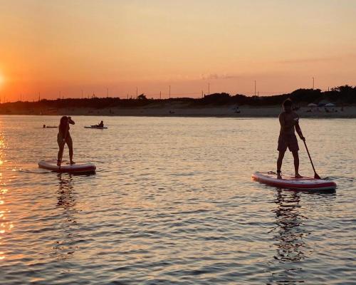 two men are paddleboarding on the water at sunset at Chill Garden Experience B&B in San Pietro in Bevagna