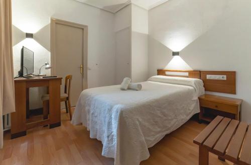 a bedroom with a bed and a table and a desk at Hotel Pedro Torres in Cuenca