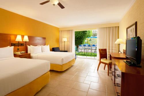 a hotel room with two beds and a television at Fiesta Americana Hacienda Ixtapan de La Sal in Ixtapan de la Sal