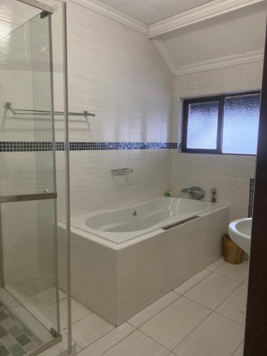 a white bathroom with a tub and a sink at Dwengu Guest house in Margate