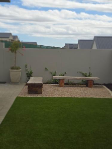 a bench in a yard with a white wall at Fifty Ridge in George