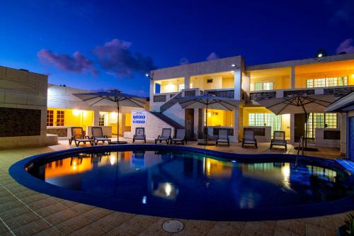 a pool in front of a building at night at Carambola Hotel with Pool Access, Steps to Beach in Christ Church