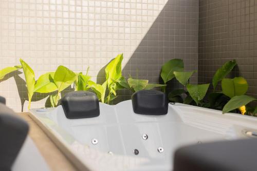 a white bath tub with green plants in a bathroom at Beach Haus #05 - Studio com Jacuzzi por Carpediem in João Pessoa