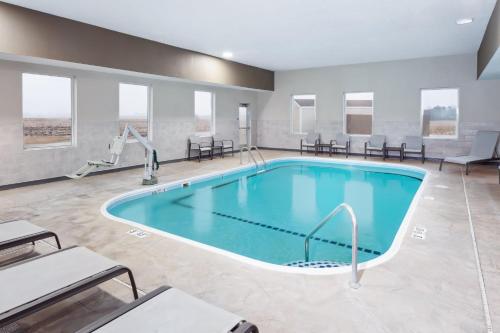 a pool in a hotel room with chairs and tables at Holiday Inn Express Pekin - Peoria Area by IHG in Pekin Heights