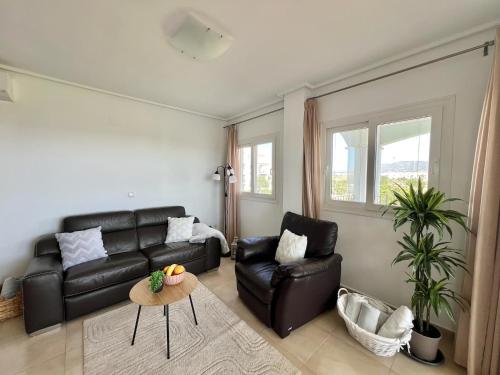 a living room with a black leather couch and a table at Beautiful apartment with golf and mountains view in Sucina
