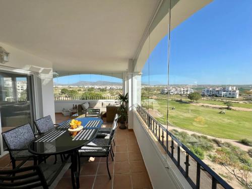 a balcony with a table and chairs and a large window at Beautiful apartment with golf and mountains view in Sucina