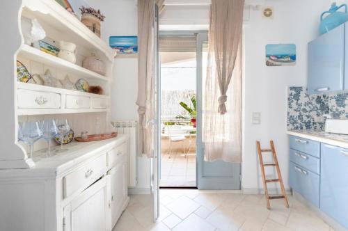 a kitchen with white cabinets and a blue door at Le Terrazze in Otranto