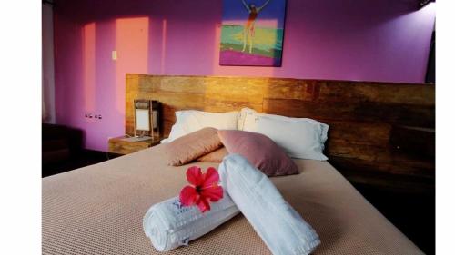 a bed with two towels and a red flower on it at Pousada Arágua in Bombinhas
