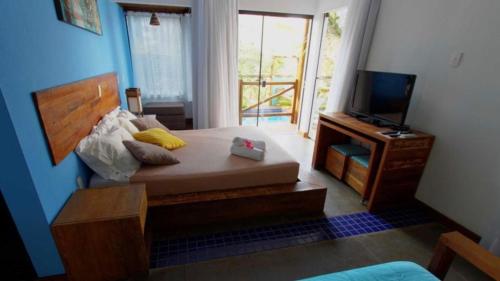 a bedroom with a large bed and a television at Pousada Arágua in Bombinhas