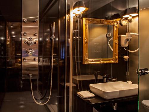 a bathroom with a shower and a sink and a mirror at Hotel Betmanowska Main Square Residence Adults Only in Kraków