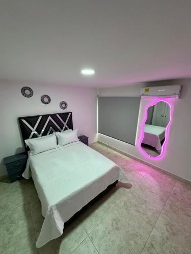 a bedroom with a white bed and a pink light at Apartamento en el centro de Tuluá in Tuluá