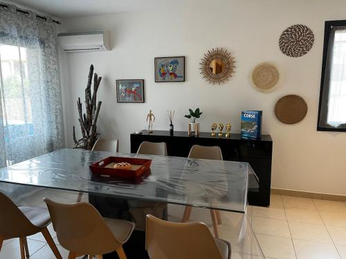 une salle à manger avec une table et des chaises en verre dans l'établissement Appart, résidentiel penta-di-Casinca, à Penta-di-Casinca