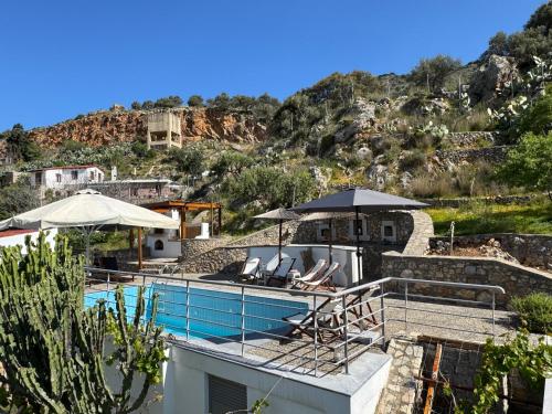 a villa with a swimming pool with chairs and umbrellas at Stone Heaven Villa -Poolside BBQ & Fresh Herbs in Nikithianós