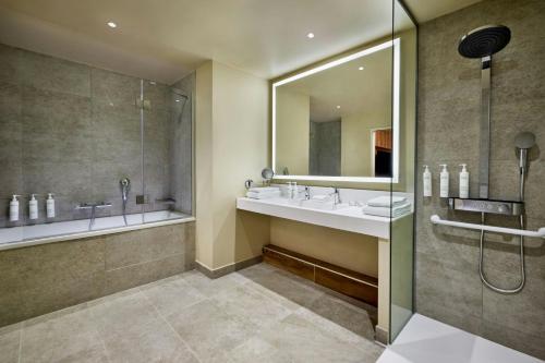 a bathroom with a sink and a shower and a mirror at Courtyard by Marriott Lyon Eurexpo Stadium in Genas