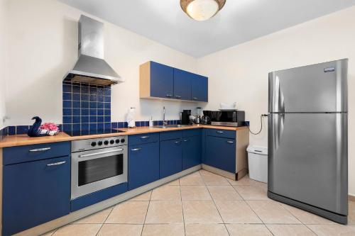 uma cozinha com armários azuis e uma geladeira de aço inoxidável em Palma Real 29 em Palm Beach